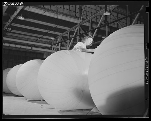 Flotation bag manufacturing. Woman balloon room worker applying finishing touches to inflatable flotation bags used to float marine aircraft forced down at sea. Goodyear, Akron, Ohio