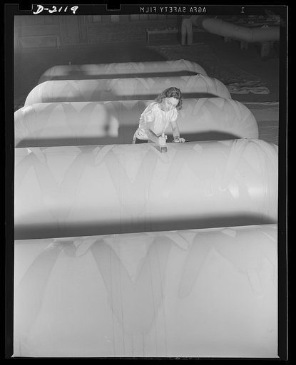 Flotation bag manufacturing. Woman balloon room worker applying finishing touches to inflatable flotation bags used to float marine aircraft forced down at sea. Goodyear, Akron, Ohio