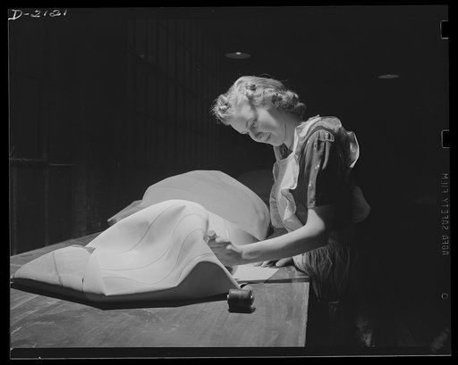 Aircraft life raft manufacturing. Woman worker in balloon room applies tape to inflatable seat which will become part of emergency life raft for military aircraft. Goodyear, Akron, Ohio