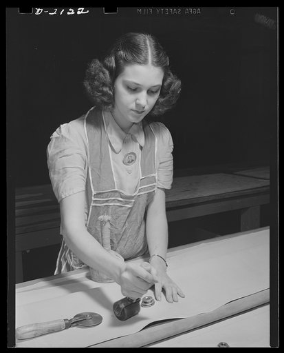 Aircraft life raft manufacturing. Valve fitting for emergency life raft for military aircraft is applied by balloon room worker with special tools. Goodyear, Akron, Ohio