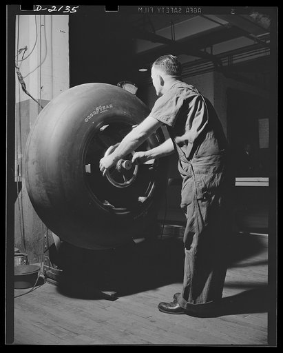 Aircraft tire manufacture. Every airplane tire for military aircraft is carefully balanced on a special machine to guarantee flawless performance in service. Inspector is making final check on airplane tires destined for military service. Goodyear, Akron, Ohio