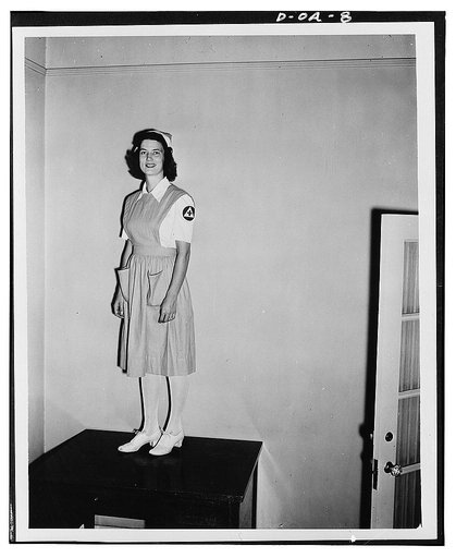 Jane Womack models new uniform selected for 100,000 defense volunteers to be trained as nurse's aides by the American Red Cross. The training project, in collaboration with the Office of Civilian Defense, is designed to relieve the acute shortage of nursing service threatening civilian hospitals and