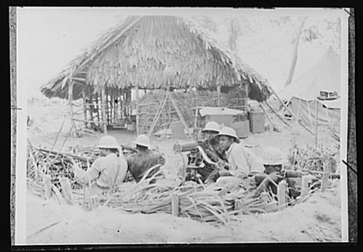 U.S. forces establish bases in Liberia. These American soldiers stationed in Liberia, Africa, are guarding a dock where supplies are being unloaded. The thatched hut in the background is a repair shop. Chiefly Negro units, the American forces are constructing bridges, improving roads, building air b