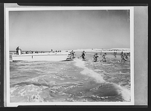 Marines. Invasion maneuvers. In a simulated invasion, U.S. Marines leap from the landing barges which ferried them from their transport vessels to the shore and dash through the surf to take up positions on the beach. This picture was taken during maneuvers at the Marine base, Camp Lejeune