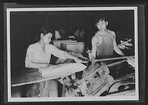 Here is one of the old-fashioned rolling machines which may still be found, in diminishing quantity in rubber plants in the Netherlands East Indies. These workers are flattening latex slices into sheet for shipment