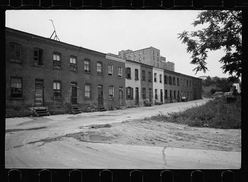 Untitled photo, possibly related to: Block of slum houses with outside toilets and water supply, hotel to the left and the round roof of Union Station in the right background, Washington, D.C.