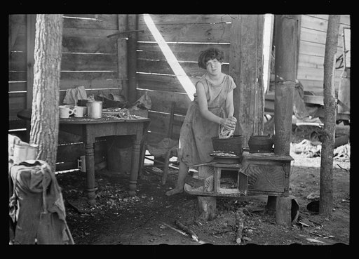 Twelve-year old girl of family of nine, cooking meal in rude, open lean-to near hut, Tennessee