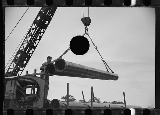 Untitled photo, possibly related to: Unloading pipe with crane, Greenbelt, Maryland