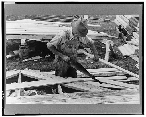 Carpenter working on gable of prefabricated house, Roanoke Farms, North Carolina