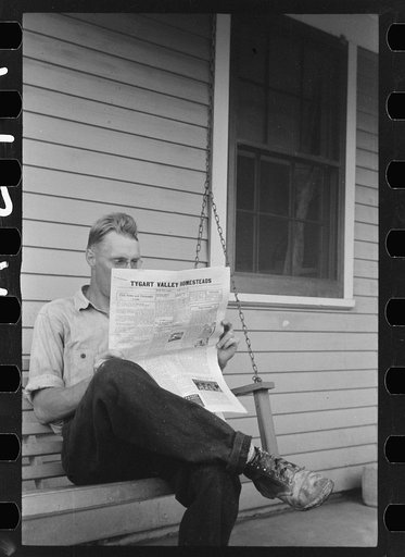 Tygart Valley homesteader reading project newspaper, West Virginia