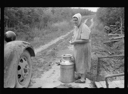 Mrs. Howard with can of milk which truck driver is calling for. Aitkin County, Minnesota
