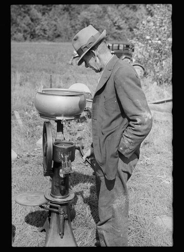 Untitled photo, possibly related to: Farmer examining cream separator. Auction near Tenstrike, Minnesota