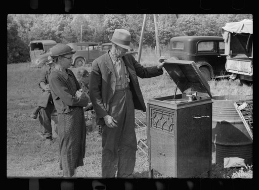 Farmer and wife examining phonograph at auction near Tenstrike, Minnesota