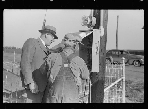 Untitled photo, possibly related to: County agent and farmer looking at electric meter on farm, Grundy County, Iowa