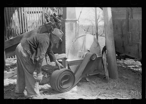 Winding up belt which extended from tractor to operate corn grinder, Grundy County, Iowa