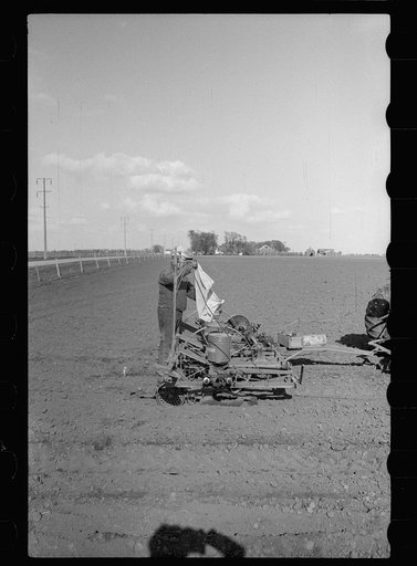 Pouring corn in box of tractor planter, Jasper County, Iowa