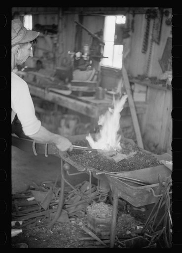 Untitled photo, possibly related to: Blacksmith heating plow point, Southeast Missouri Farms