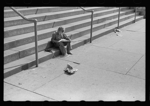 Boy reading funny paper on steps of public library, Milwaukee, Wisconsin