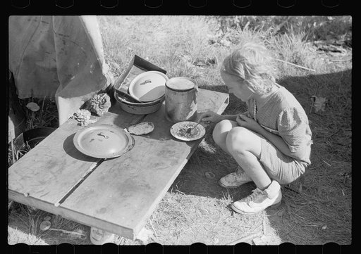 Migrant child eating in front of tent home, Berrien County, Michigan