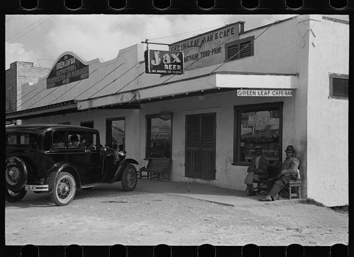 Shiney new automobiles, bars and dance halls are found among the squalid shacks in the Negro section of Belle Glade, Florida