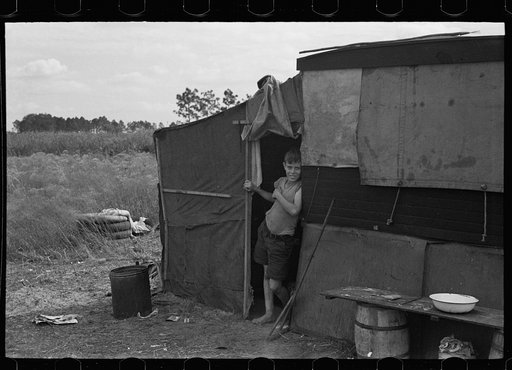 Son of a migrant family in the doorway of his temporary home near Winter Haven, Florida
