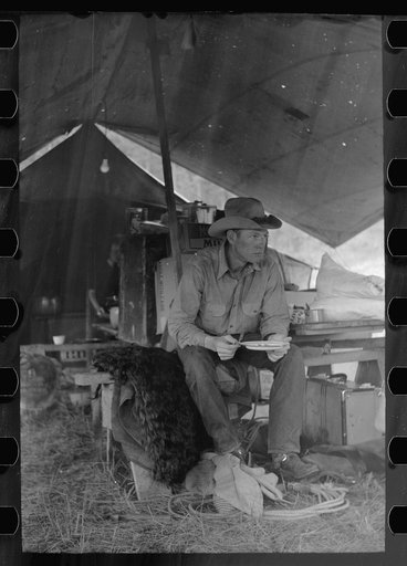Cowboy eating in Three Circle roundup camp, Powder River County, Montana