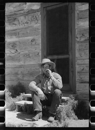 Cowboy in front of bunkhouse, Quarter Circle U Ranch, Big Horn County, Montana