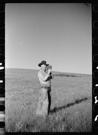 Cowboy with amateur movie camera, Quarter Circle U roundup, Montana