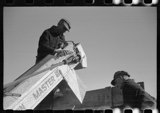 Farmer adjusts corn picker at mechanical cornhusking contest, Hardin County, Iowa