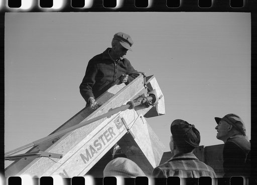Untitled photo, possibly related to: Farmer adjusts corn picker at mechanical cornhusking contest, Hardin County, Iowa