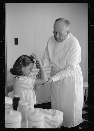 Doctor examines fractured arm, FSA (Farm Security Administration) camp clinic, Weslaco, Texas