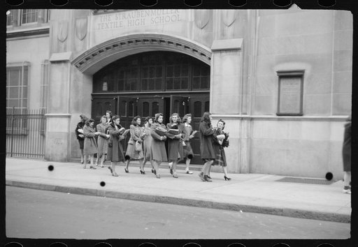 Schoolgirls walking along street in front of Straubenmuller Textile High School, New York, New York