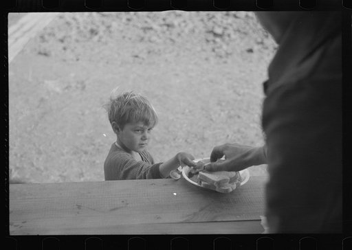 Small boy at mealtime in the camp for white flood refugees, Forrest City, Arkansas