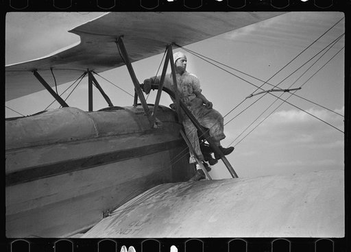 Untitled photo, possibly related to: "Duster" plane spraying insecticide over a field of beans. The mechanic in the foreground indicates the outside limit of the last "swath" which has settled by the time the plane returns. Note how low the plane flies. Beanfields like this, hundreds of acres in ext