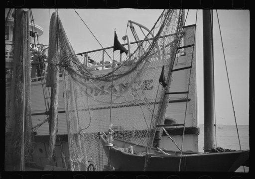 The economy of a town: fishing and the tourist trade. A fishing boat in front of the S.S. "Romance," a tourist boat which used to ply between Boston and Provincetown and has since sunk in Boston Harbor. Provincetown, Massachusetts