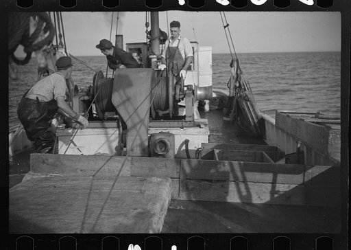 Untitled photo, possibly related to: Aboard a trawler (locally called a dragger). The power-driven winch lets out the starboard net. While over fishing grounds one of two nets is constantly in the water, dragging along the bottom. Boats are powerful, diesel-engined, between forty and seventy-five fe