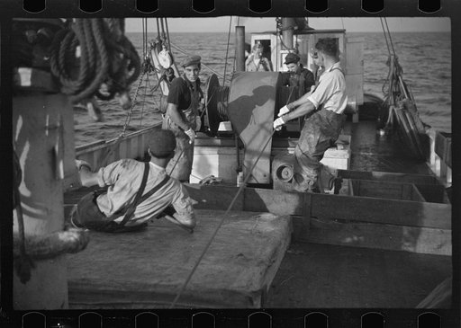 Untitled photo, possibly related to: Aboard a trawler (locally called a dragger). The power-driven winch lets out the starboard net. While over fishing grounds one of two nets is constantly in the water, dragging along the bottom. Boats are powerful, diesel-engined, between forty and seventy-five fe