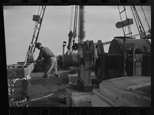 Untitled photo, possibly related to: Aboard a trawler (locally called a dragger). The power-driven winch lets out the starboard net. While over fishing grounds one of two nets is constantly in the water, dragging along the bottom. Boats are powerful, diesel-engined, between forty and seventy-five fe
