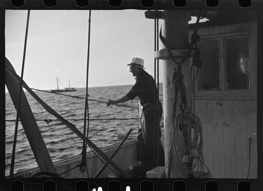 Untitled photo, possibly related to: Aboard a trawler (locally called a dragger). The power-driven winch lets out the starboard net. While over fishing grounds one of two nets is constantly in the water, dragging along the bottom. Boats are powerful, diesel-engined, between forty and seventy-five fe