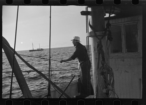 Untitled photo, possibly related to: Aboard a trawler (locally called a dragger). The power-driven winch lets out the starboard net. While over fishing grounds one of two nets is constantly in the water, dragging along the bottom. Boats are powerful, diesel-engined, between forty and seventy-five fe