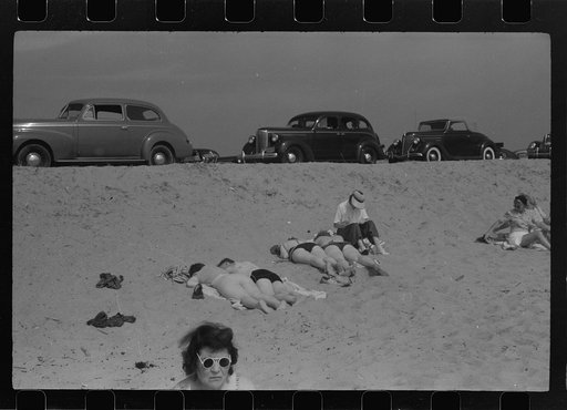 Beach scene at "New Beach," the most popular beach near Provincetown. Regular bus service makes this beach easily available; lack of bath houses causes a great deal of picturesque dressing and undressing in and behind parked cars. Provincetown, Massachusetts