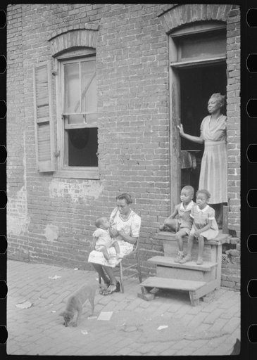 Negro family in front of their alley dwelling. The older woman is a cleaning woman in the U.S. government. Washington, D.C.