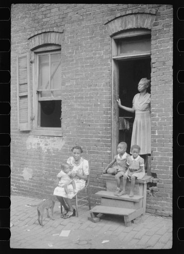 Untitled photo, possibly related to: Negro family in front of their alley dwelling. The older woman is a cleaning woman in the U.S. government. Washington, D.C.