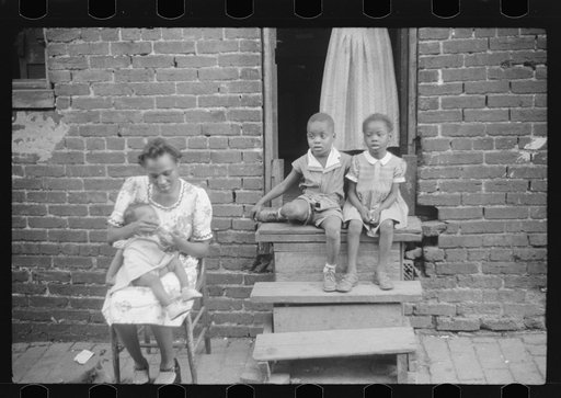 Untitled photo, possibly related to: Negro family in front of their alley dwelling. The older woman is a cleaning woman in the U.S. government. Washington, D.C.