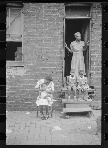 Untitled photo, possibly related to: Negro family in front of their alley dwelling. The older woman is a cleaning woman in the U.S. government. Washington, D.C.