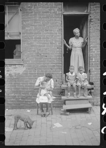 Untitled photo, possibly related to: Negro family in front of their alley dwelling. The older woman is a cleaning woman in the U.S. government. Washington, D.C.