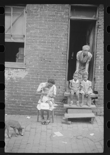 Untitled photo, possibly related to: Negro family in front of their alley dwelling. The older woman is a cleaning woman in the U.S. government. Washington, D.C.