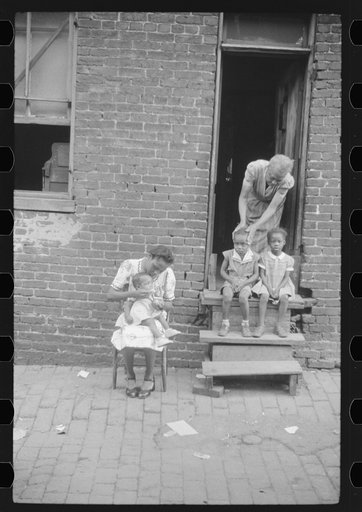 Untitled photo, possibly related to: Negro family in front of their alley dwelling. The older woman is a cleaning woman in the U.S. government. Washington, D.C.