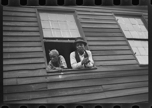Untitled photo, possibly related to: Negro quarter, Natchez, Mississippi. The home of a Negro family with a Negro man and a woman looking out a window
