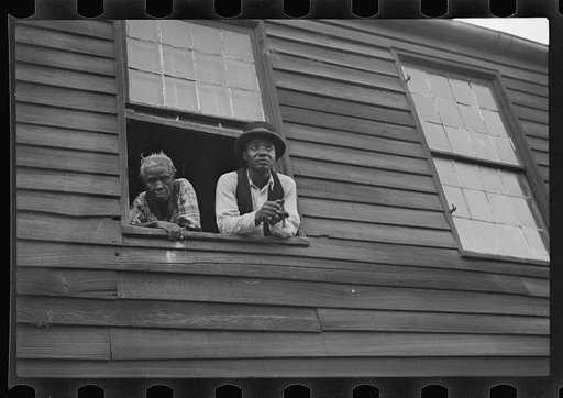 Negro quarter, Natchez, Mississippi. The home of a Negro family with a Negro man and a woman looking out a window